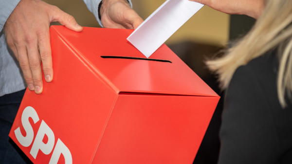 Eine Frau steckt einen Wahlzettel in eine Wahlurne